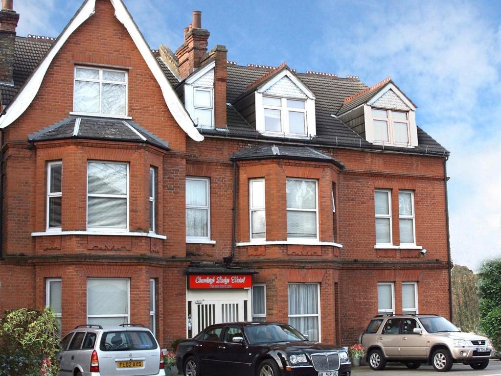 a red brick house with two cars parked in front of it at Chumleigh Lodge Hotel Ltd. in Hendon