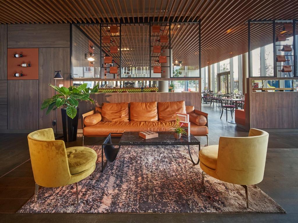 uma sala de estar com um sofá e duas cadeiras em Golden Tulip Bordeaux Euratlantique em Bordéus