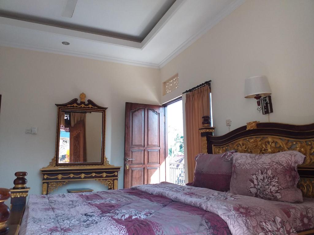 een slaapkamer met een groot bed en een spiegel bij Puri Asri Bungalow Ubud in Ubud