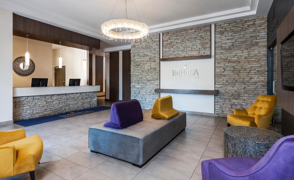 - un hall avec des fauteuils jaunes et violets et un canapé dans l'établissement Imperia Hôtel et Suites Terrebonne, à Terrebonne