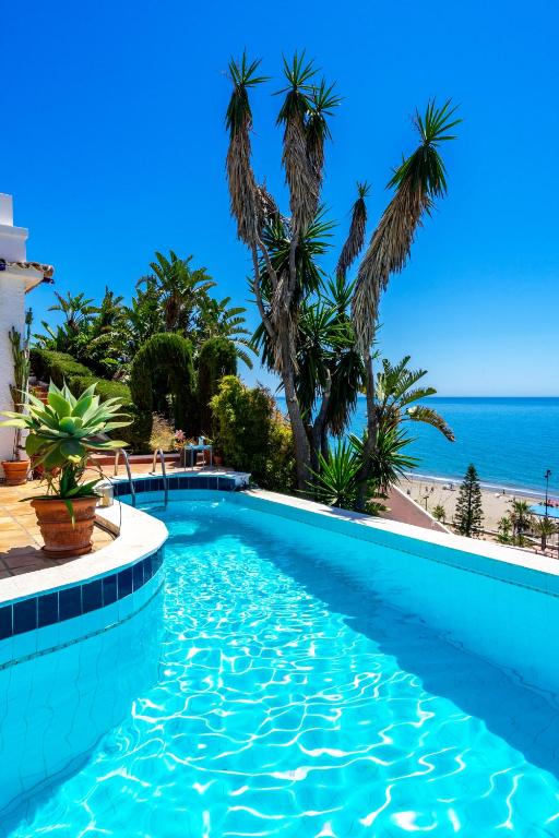 a swimming pool with palm trees and the beach at Stunning Beachclose Villa by Costarentals - Ref 03 in Fuengirola