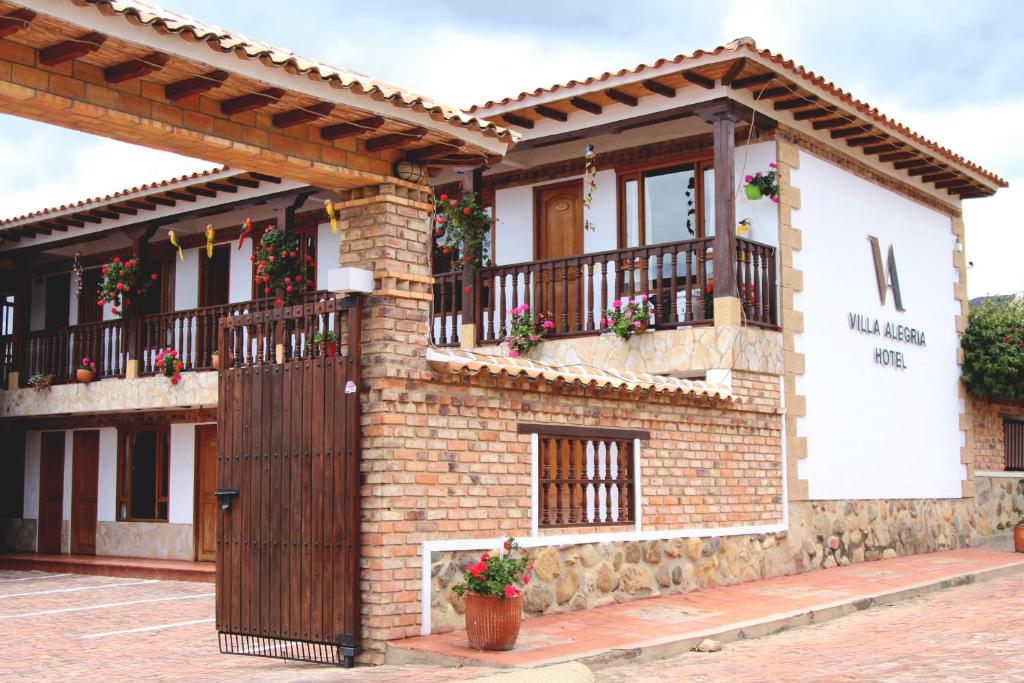 a brick building with a wooden door and balcony at Hotel Villa Alegria in Sáchica
