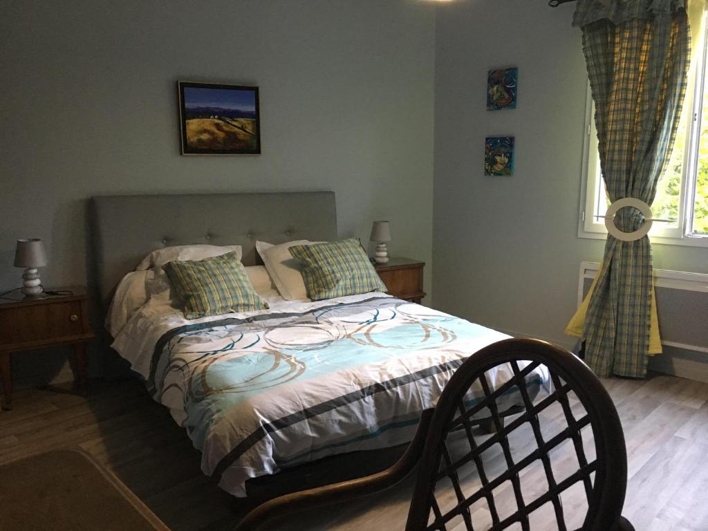 a bedroom with a bed and two windows at chambre d'hôtes du Luquet in Chazelles