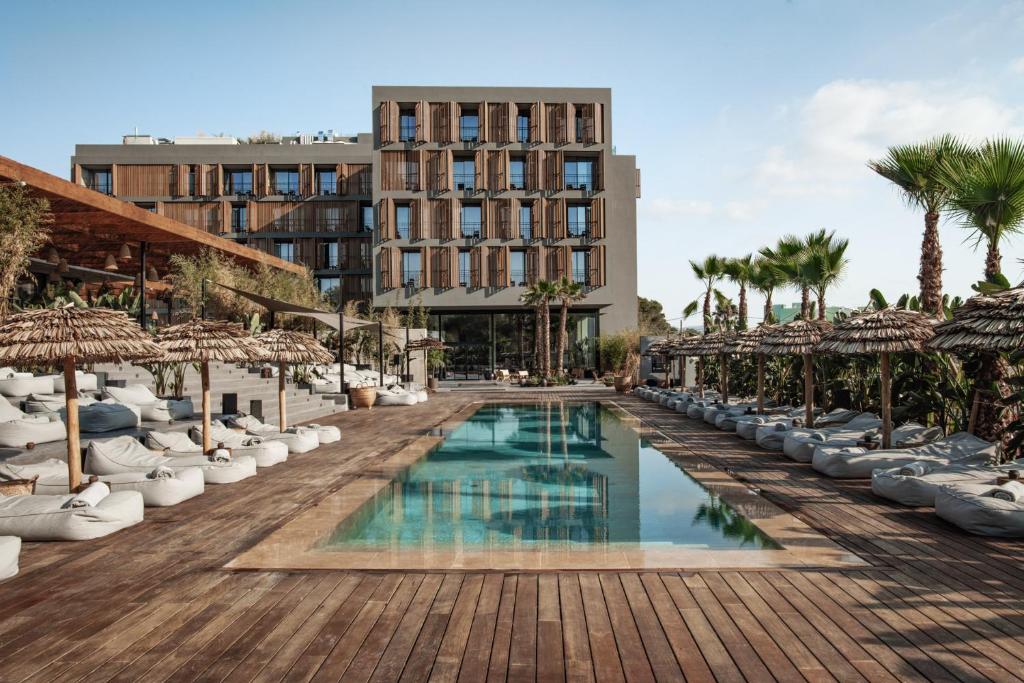 a resort with a swimming pool and palm trees at OKU Ibiza in San Antonio