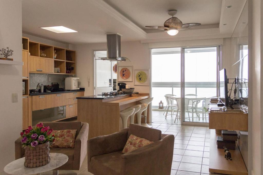 a kitchen and living room with a table and chairs at Lindo apartamento frente para o mar in Guarujá