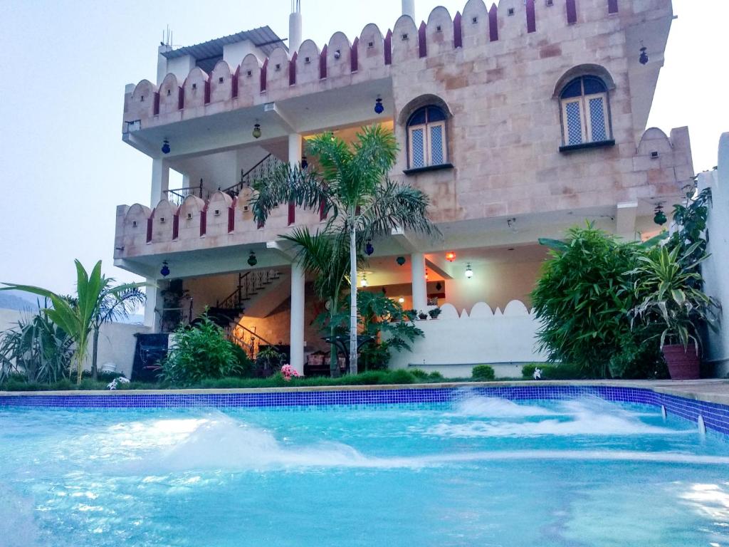 a house with a swimming pool in front of it at Hotel Vamdev Fort in Pushkar