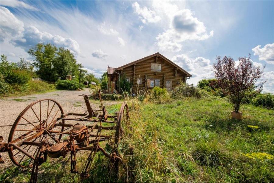 a barn and a tractor in front of a field at Le Chalet du Chemin et sa Roulotte in Berviller-en-Moselle