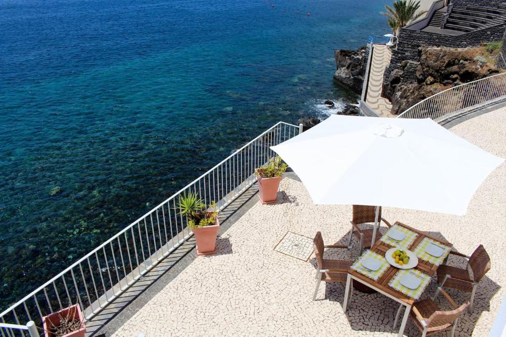 a table and chairs with an umbrella next to the ocean at The Artist Villa in Santa Cruz
