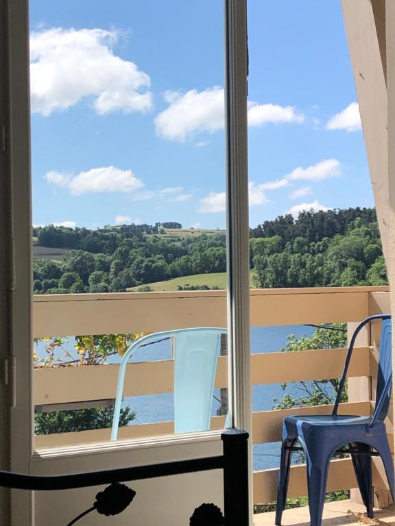 ein Fenster mit 2 Stühlen und Blick auf das Wasser in der Unterkunft MARIUS in Aydat