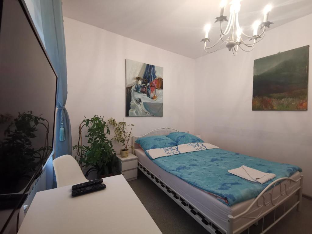 een slaapkamer met een bed, een tafel en een kroonluchter bij Apartament wygodny S3 in Kalisz