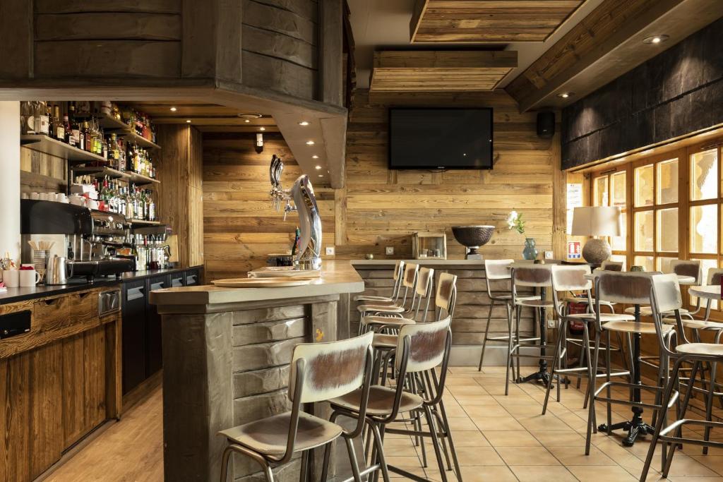a bar in a restaurant with wooden walls and stools at Résidence Les Balcons de Val Thorens & Spa in Val Thorens