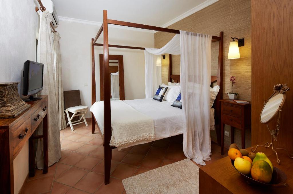 ヴィラモウラにあるHotel Parque das Laranjeirasのベッドルーム(天蓋付きベッド1台、フルーツ1杯付)