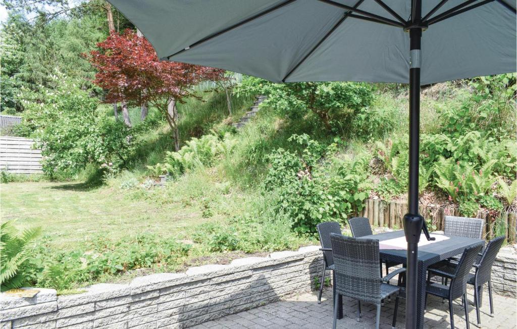 a table and chairs with an umbrella on a patio at Nice Home In Randbl With Kitchen in Randbøl