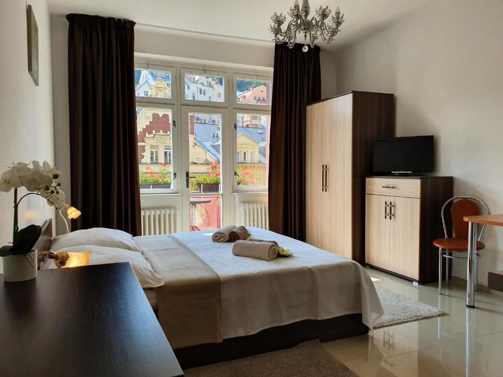 a bedroom with a bed and a large window at Madonna Apartments in Karlovy Vary