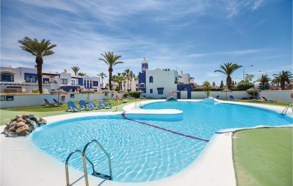 una piscina en un complejo con palmeras y casas en Nice Home In Roquetas De Mar With Kitchenette, en Roquetas de Mar