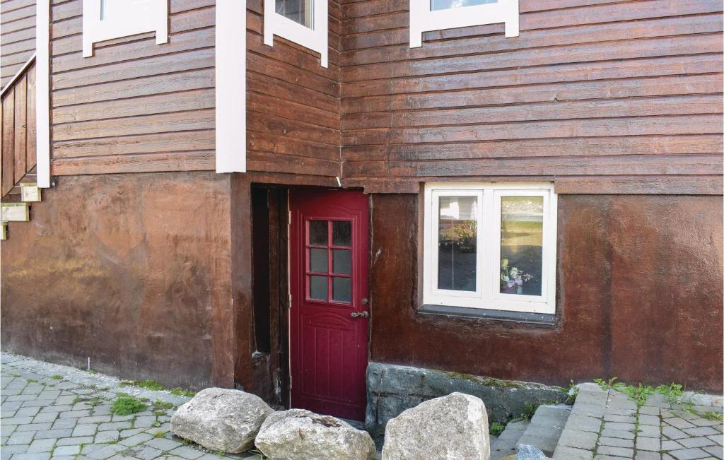 una puerta roja en el lateral de una casa de madera en 3 Bedroom Gorgeous Apartment In Giske, en Gjuv