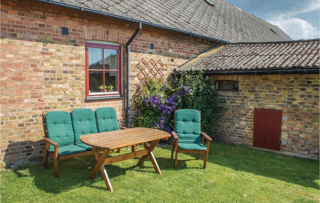 two chairs and a wooden table in front of a brick building at Nice Home In Glumslv With 1 Bedrooms in Glumslöv