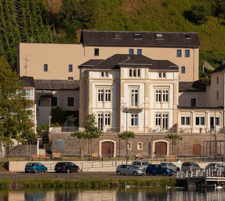 ein großes weißes Gebäude mit davor geparkt in der Unterkunft Ferienwohnungen Villa Mosella in Bernkastel-Kues