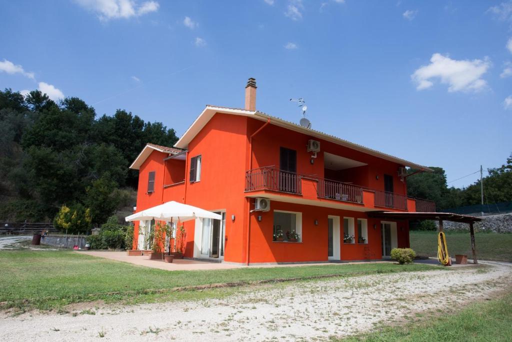 ein rotes Haus mit einem Balkon an der Seite in der Unterkunft GUEST HOUSE IL LEONE in Viterbo