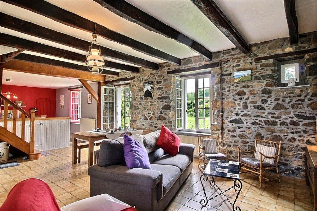 a living room with a couch and a stone wall at Holiday home Le Gite de Kerneuil in Gommenecʼh