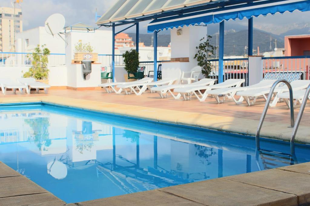 una piscina en la azotea de un edificio con tumbonas blancas en Hotel Mareny Benidorm en Benidorm
