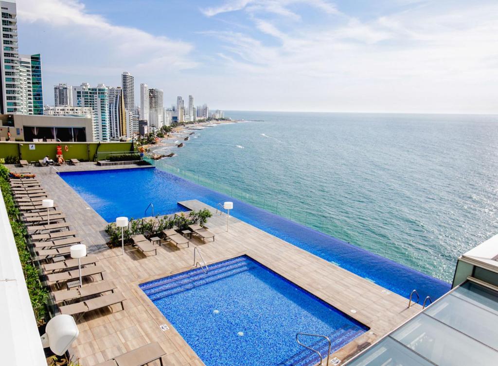 Una vista aérea de una piscina y el océano. en Apartamento en Lujoso Edificio H2 Plaza Bocagrande, en Cartagena de Indias