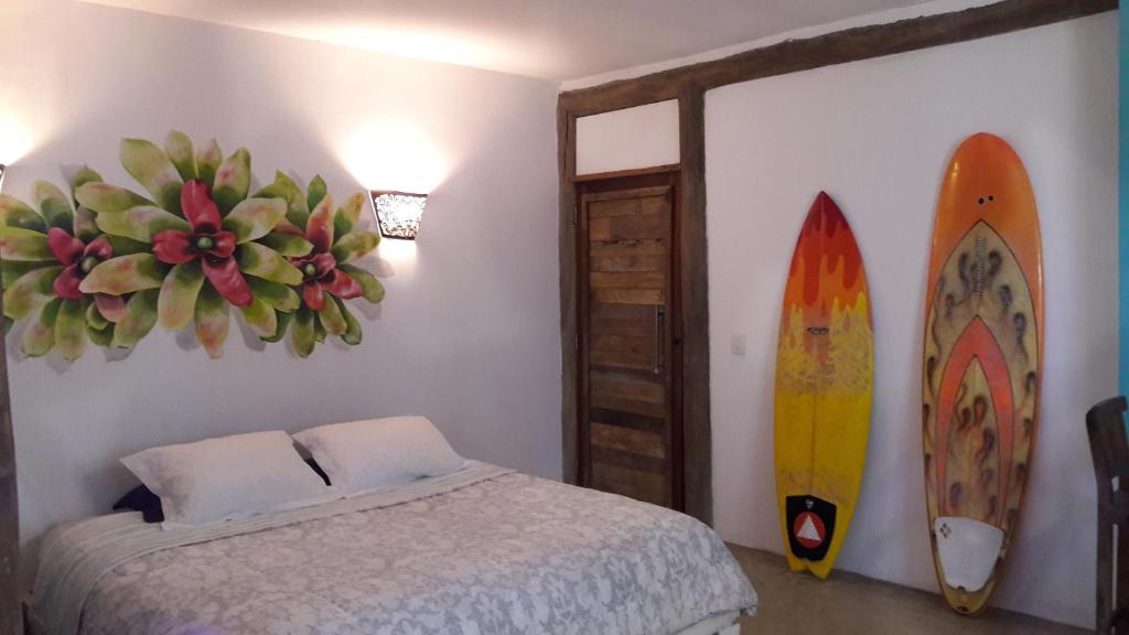 a room with a bed and surfboards on the wall at Casa das Palmeiras Pé na Areia in Ubatuba