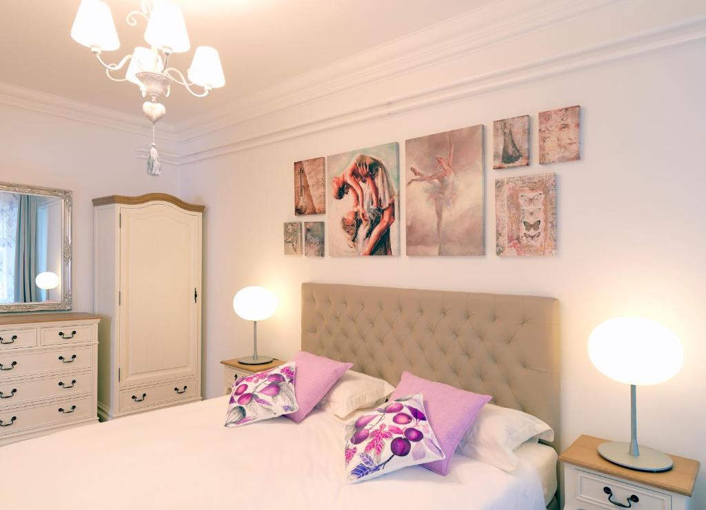 een slaapkamer met een bed met twee lampen en foto's aan de muur bij City Pearl Apartment in Ljubljana
