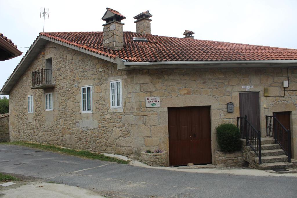 Casa de piedra con puerta y balcón en Casa Solveira en Piñeiro