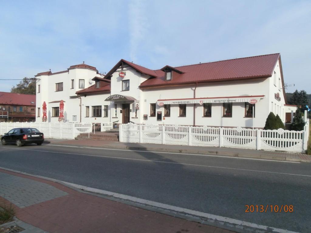 un edificio blanco al lado de una calle en Penzion Adriana, en Jiříkov