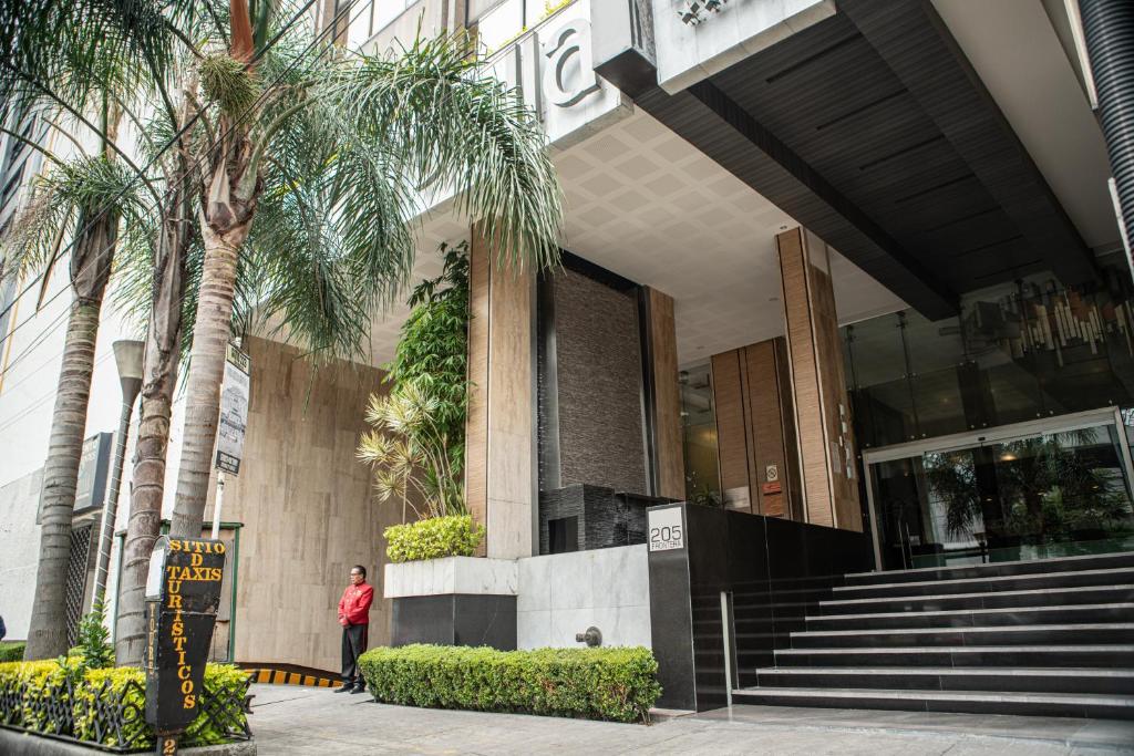 a person standing in front of a building with palm trees at Hotel Marbella in Mexico City