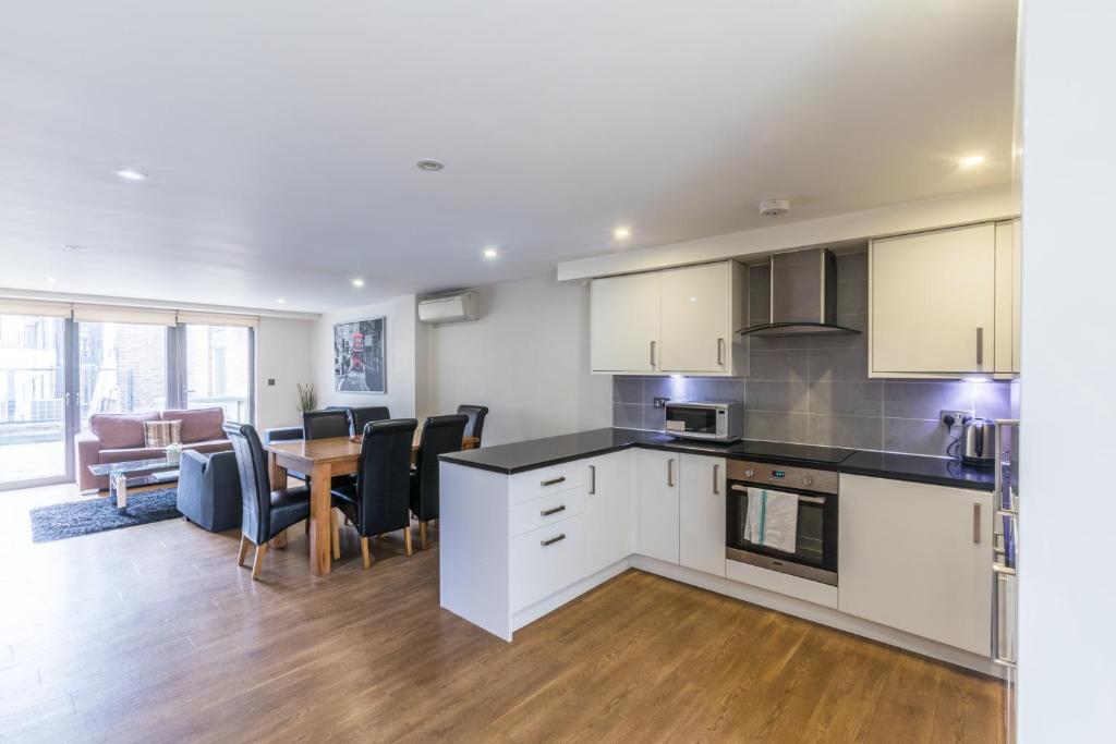 a kitchen with white cabinets and a table and chairs at Lovely 2 Bed 2 Bath Apartment Central London in London