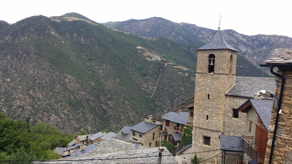 un bâtiment avec une tour d'horloge en face d'une montagne dans l'établissement CAL GERARD - ARCAVELL, à Arcabell