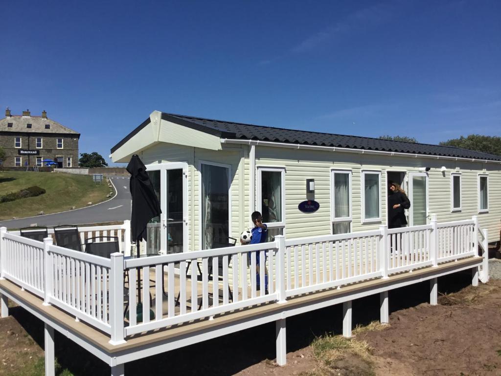 a house on a dock with two people standing on it at Lakes Retreat in Millom