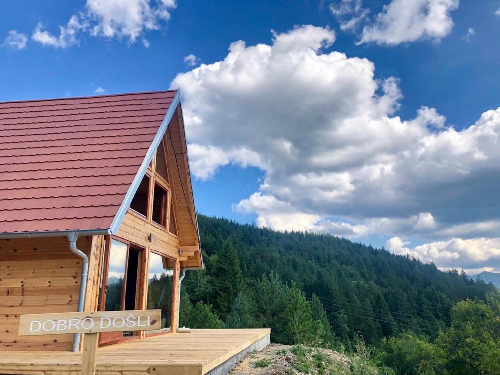 uma cabana de madeira com um telhado vermelho e uma montanha em Zaovinska idila em Bjeluša