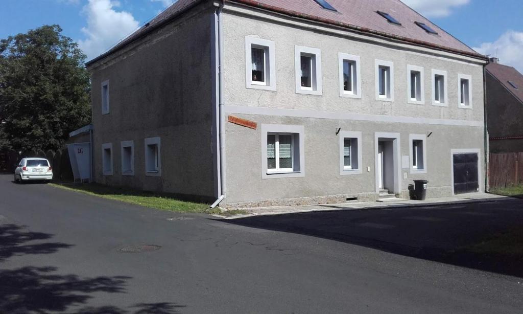 a white building with a car parked in front of it at chalupa in Hora Svatého Šebestiána