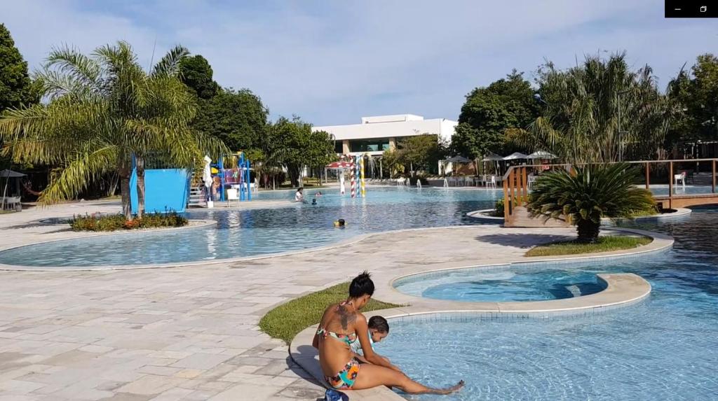 a man and a child sitting in front of a swimming pool at Iloa Residence Resort - Barra de São Miguel in Barra de São Miguel