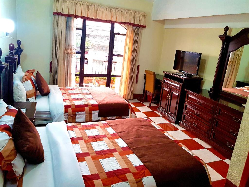 a hotel room with two beds and a television at Hotel Las Americas in Quetzaltenango