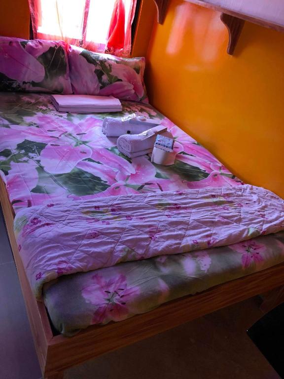 a bed with a pink blanket and shoes on it at ALERTA ROOFTOP LODGE in Magdiwang