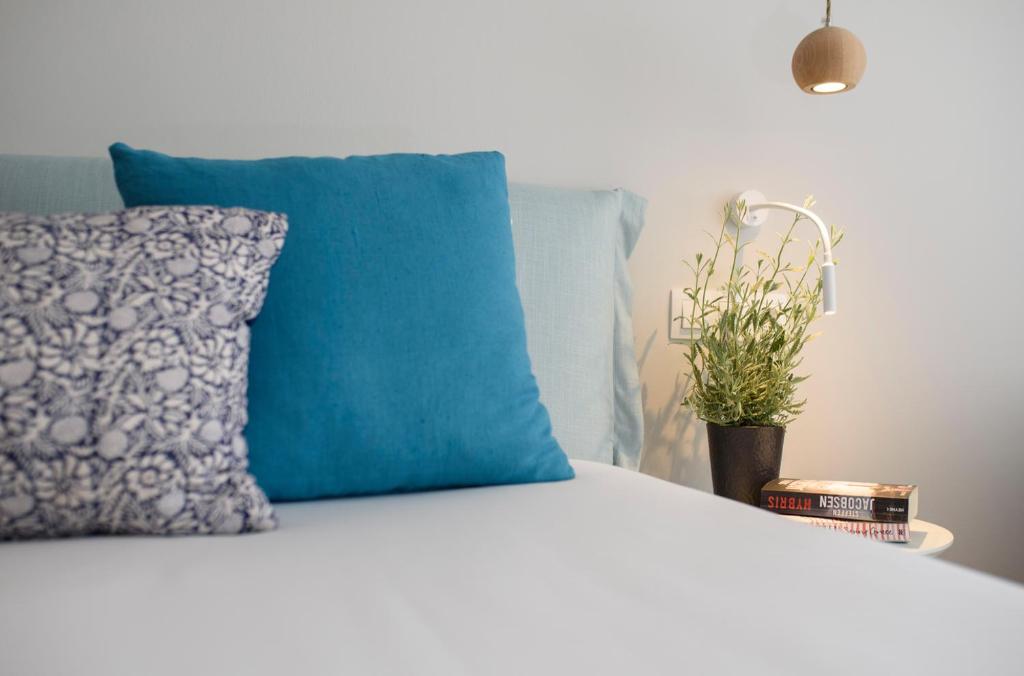 a bed with a blue pillow and a potted plant at Vigla Hotel in Aegiali