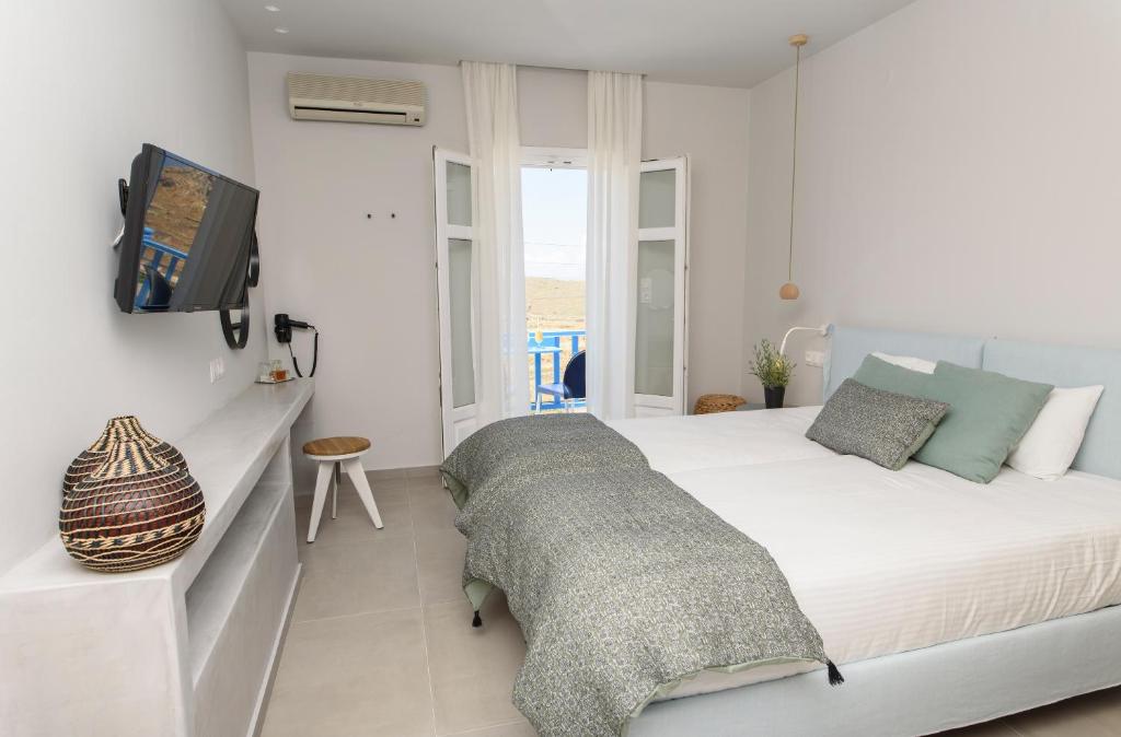 a white bedroom with a bed and a tv at Vigla Hotel in Aegiali