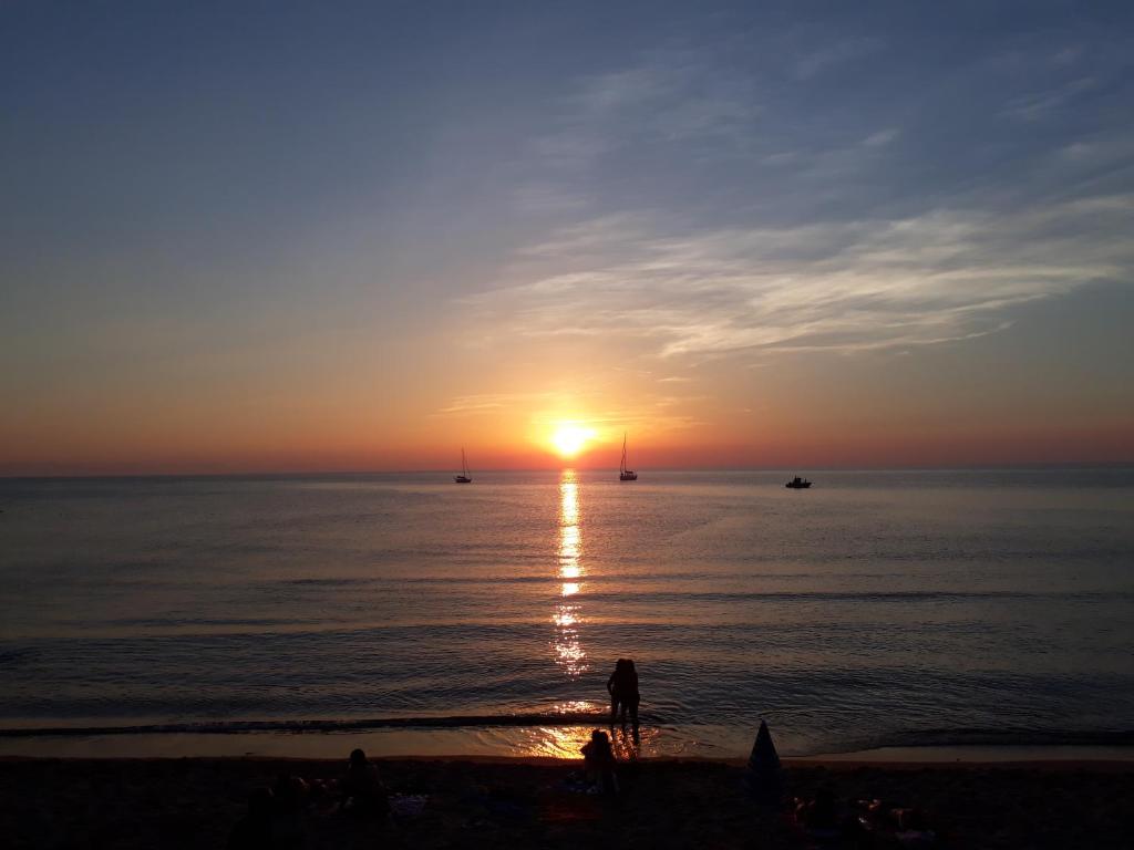 uma pessoa de pé na praia a ver o pôr-do-sol em Cortile Maggiore Home em Cefalù