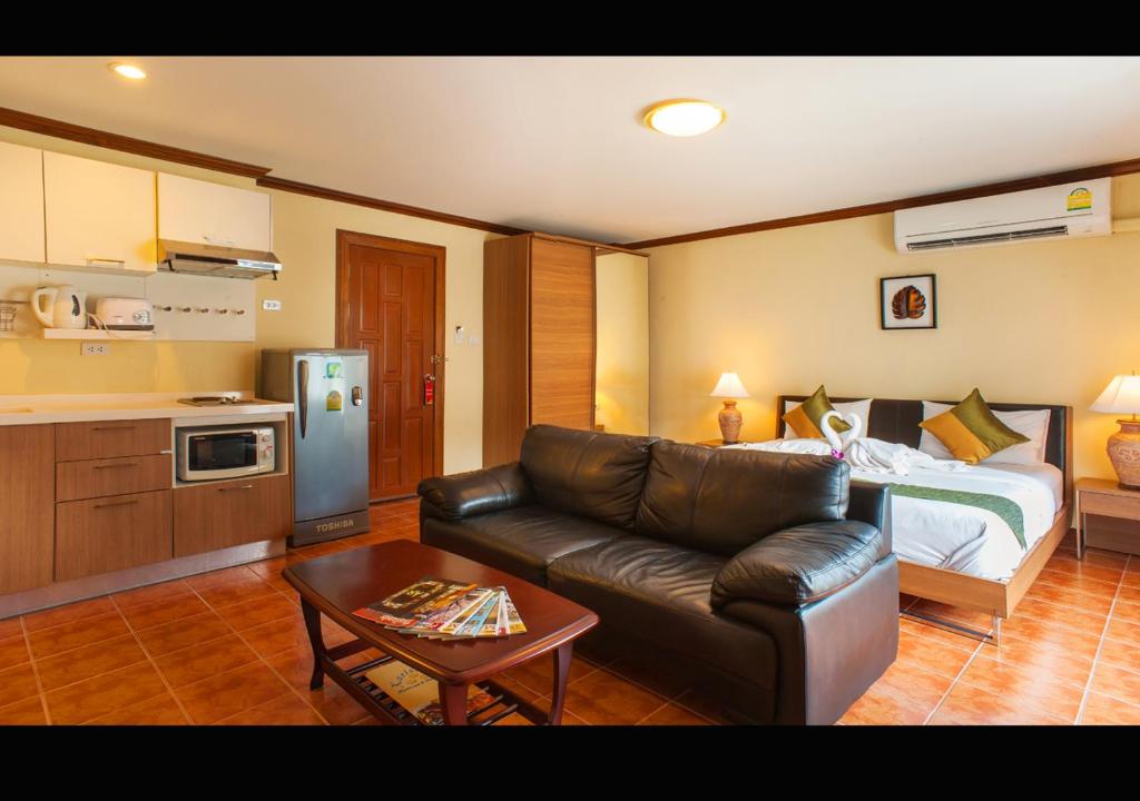 a living room with a couch and a bed at Patong Karlssons Hotel in Patong Beach