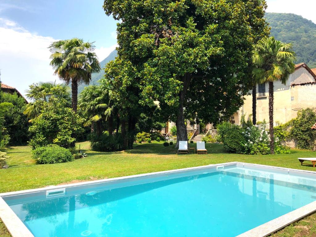 uma piscina azul num quintal com árvores em Villa Galli em Cittiglio
