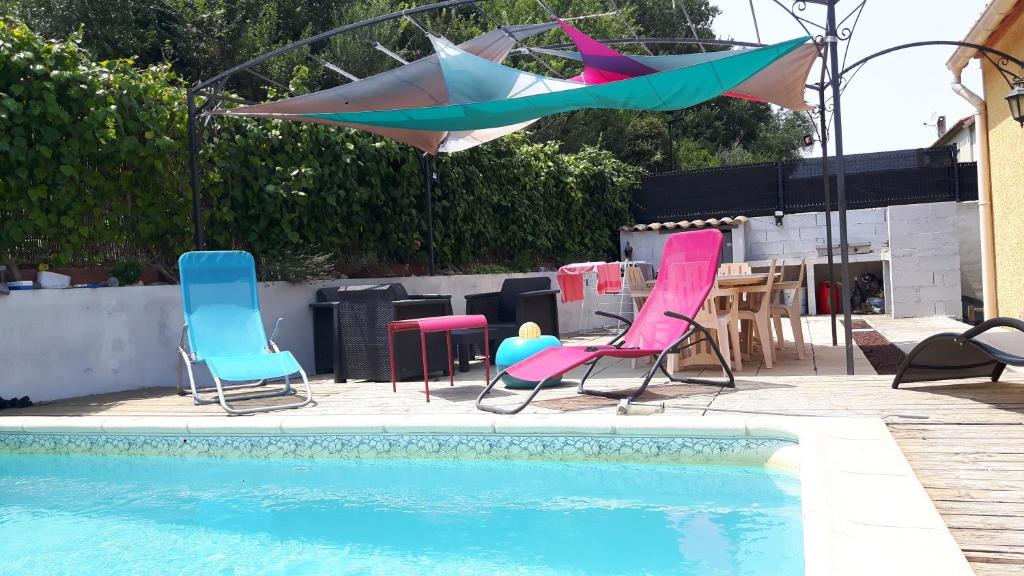 een groep stoelen en parasols naast een zwembad bij Chez Yannick et Isabelle in Saint-Nazaire