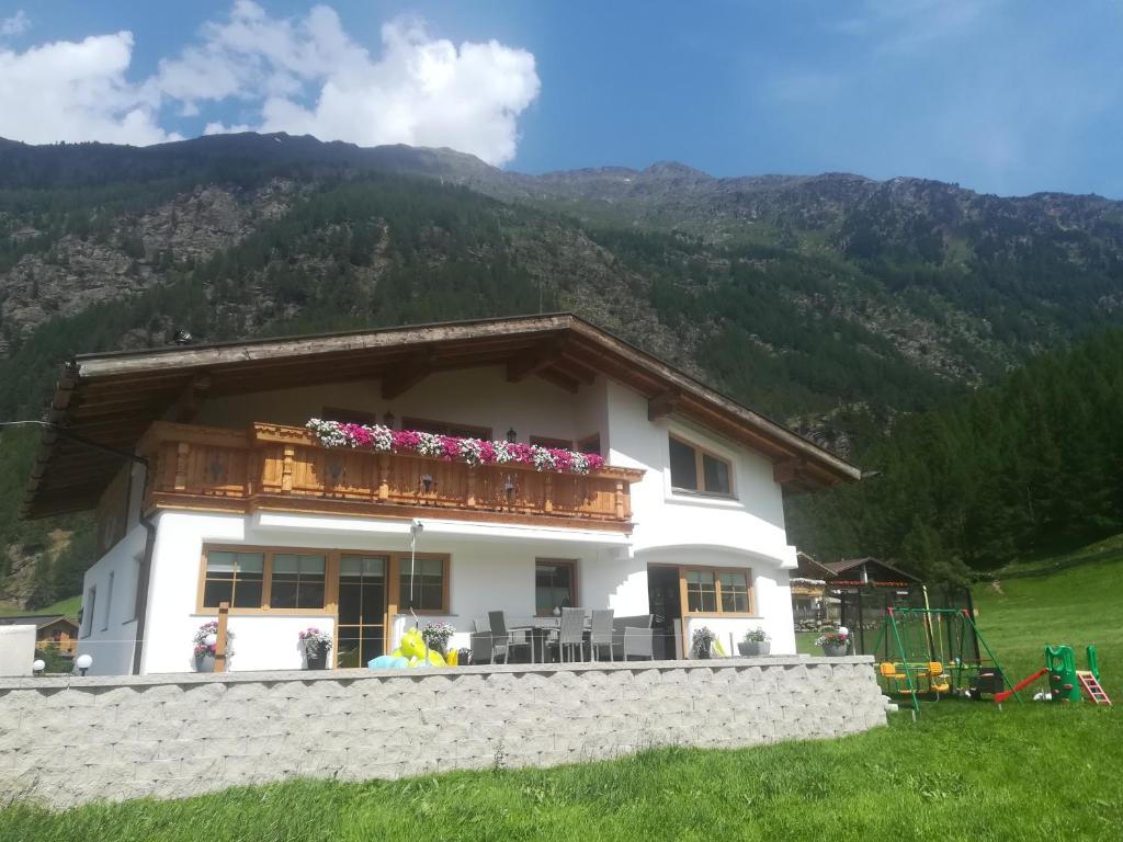 a white house with a balcony with flowers on it at Landhaus Alpenjäger in Sölden