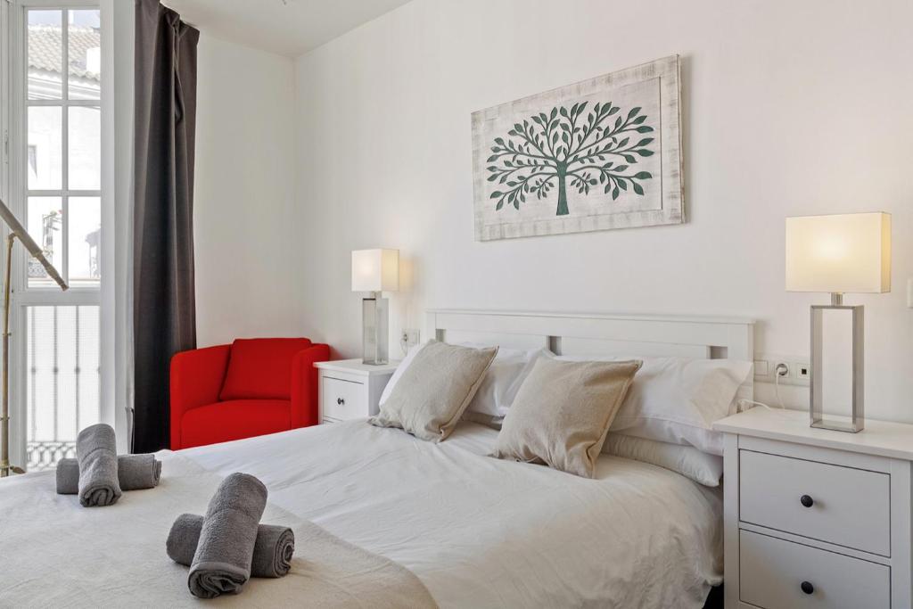 1 dormitorio con cama blanca y silla roja en Family Apartment, en Málaga