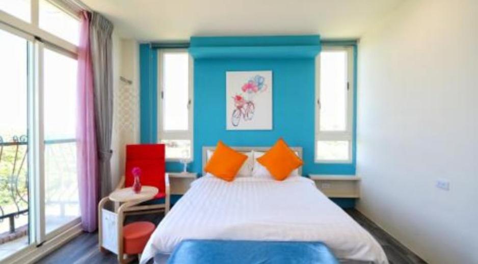 a bedroom with a bed with blue walls and windows at Full Moon Resort in Hengchun