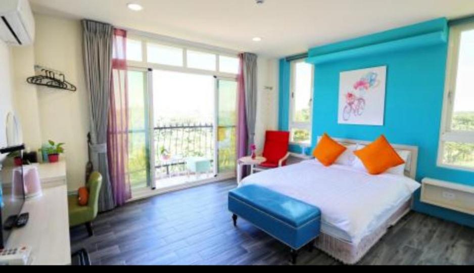 a bedroom with blue walls and a bed with orange pillows at Full Moon Resort in Hengchun