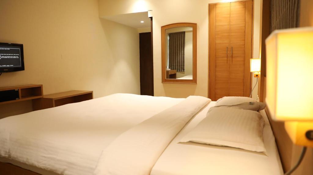 a white bed in a hotel room with a mirror at Mount Manor in Chennai